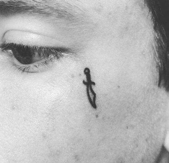 Pequeños tatuajes de dagas en la cara