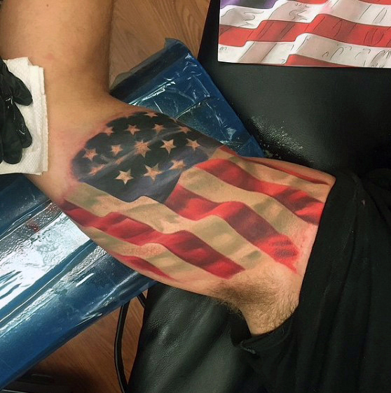 Tatuaje realista en el bíceps de la bandera de EE. UU.