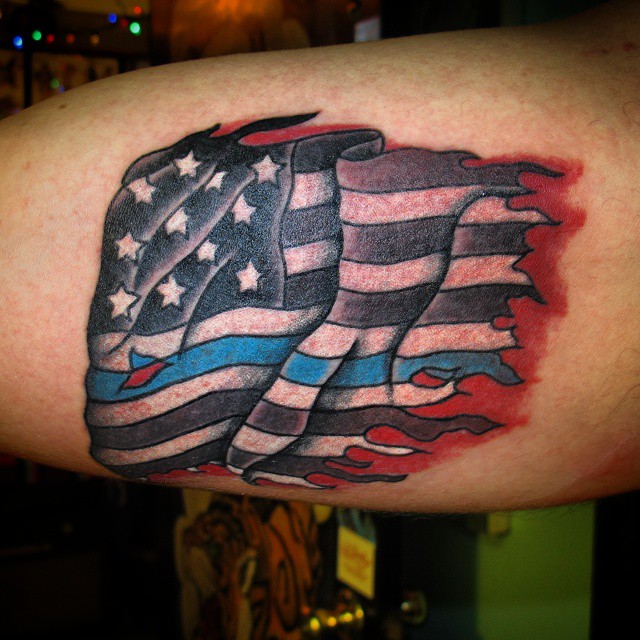 Tatuaje en el antebrazo, bandera americana rasgada