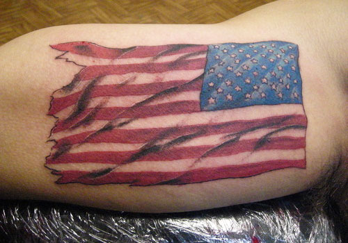 Tatuaje en el brazo, bandera americana rasgada