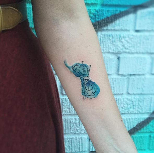 Pequeño diseño de tatuajes de tejido de color azul en el antebrazo