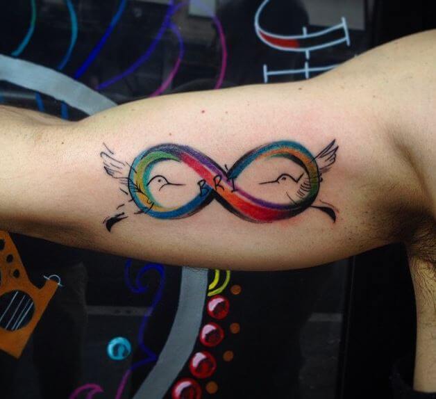 Diseños coloridos del tatuaje del infinito en el bíceps