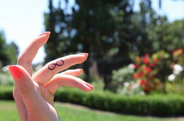 Pequeños diseños de tatuajes de infinito en los dedos medios