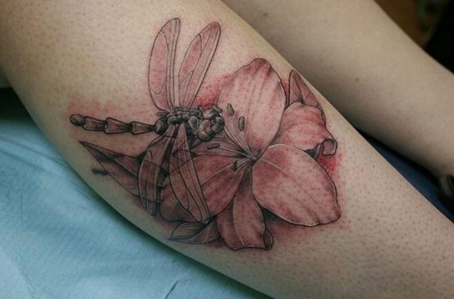 Diseño de tatuajes de libélula y flor en las piernas