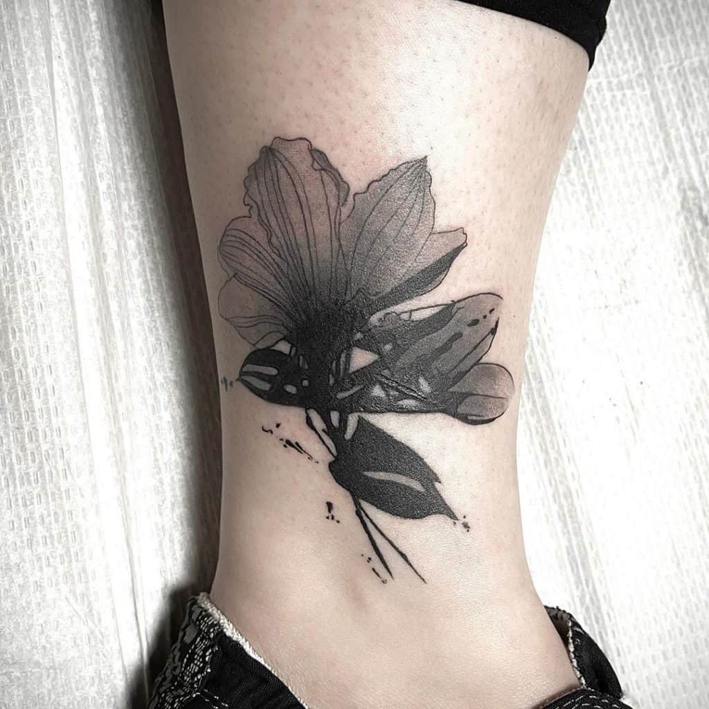 Tatuaje de flor negra en la parte inferior de la pierna.