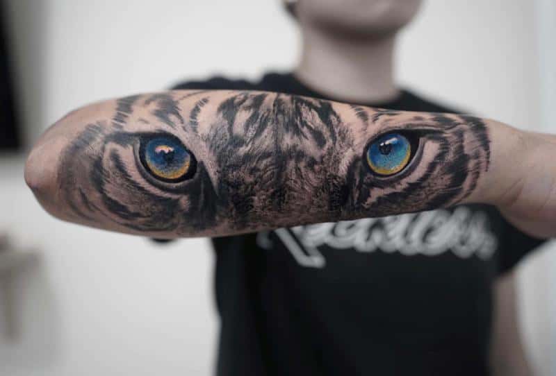 Tatuaje en el brazo, ojos de tigre amarillos y azules