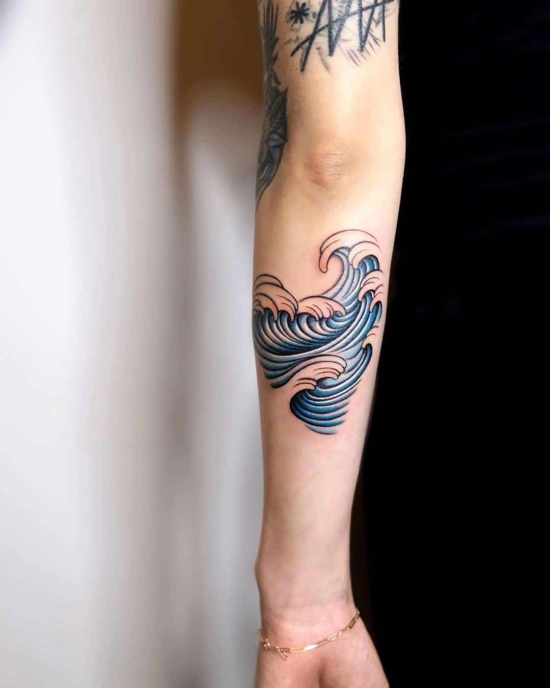 Diseño azul del tatuaje de la onda del brazo 