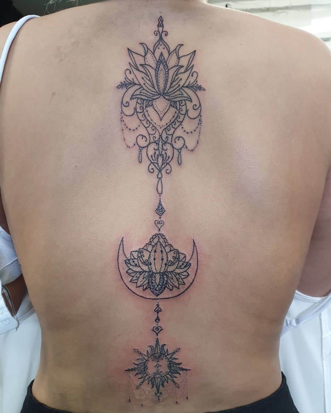 Tatuaje de flor de loto y mandala en la columna vertebral 