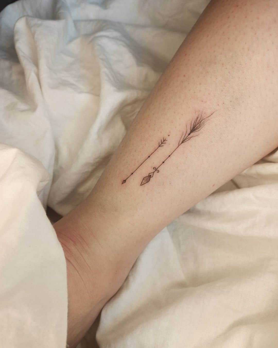 Minimalismo flecha pluma tatuaje