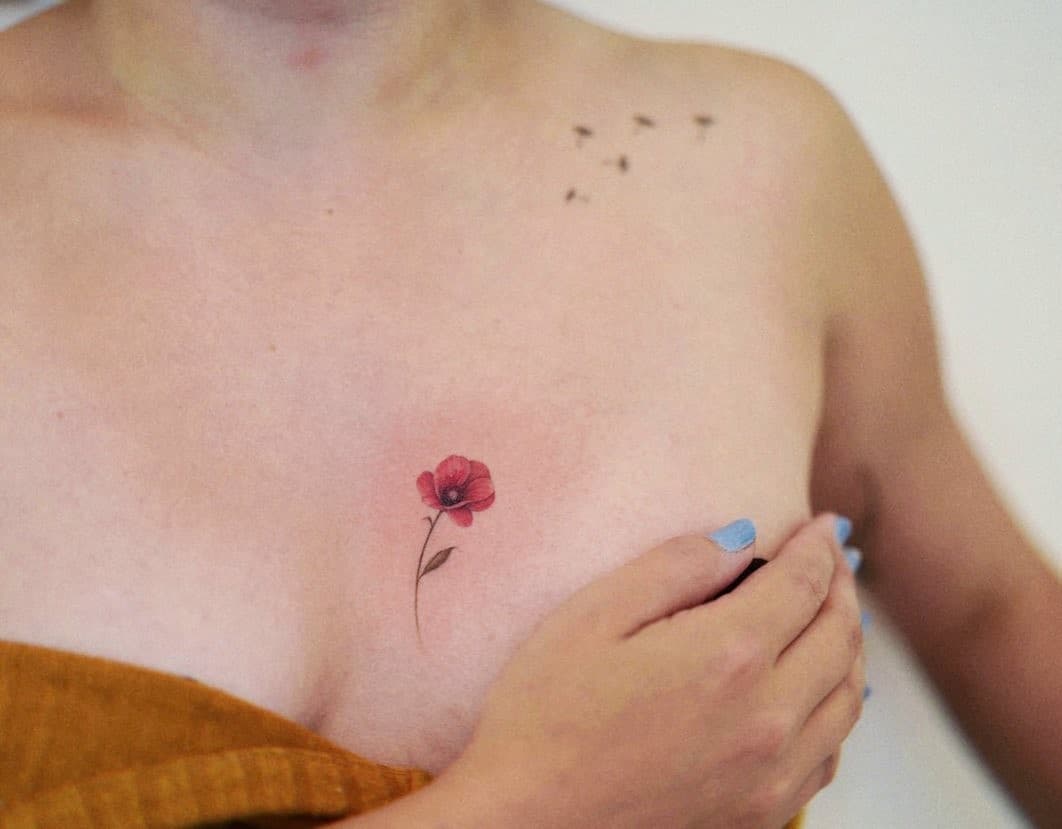 Pequeño tatuaje de flor roja pequeña sobre el pecho