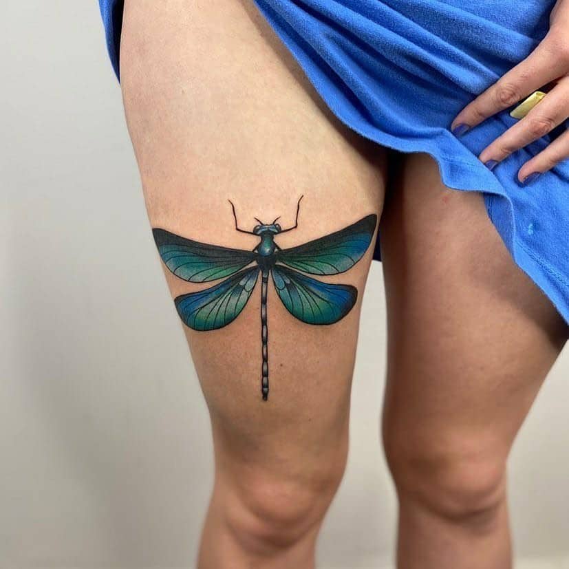 Tatuaje gigante de libélula en pierna y muslo