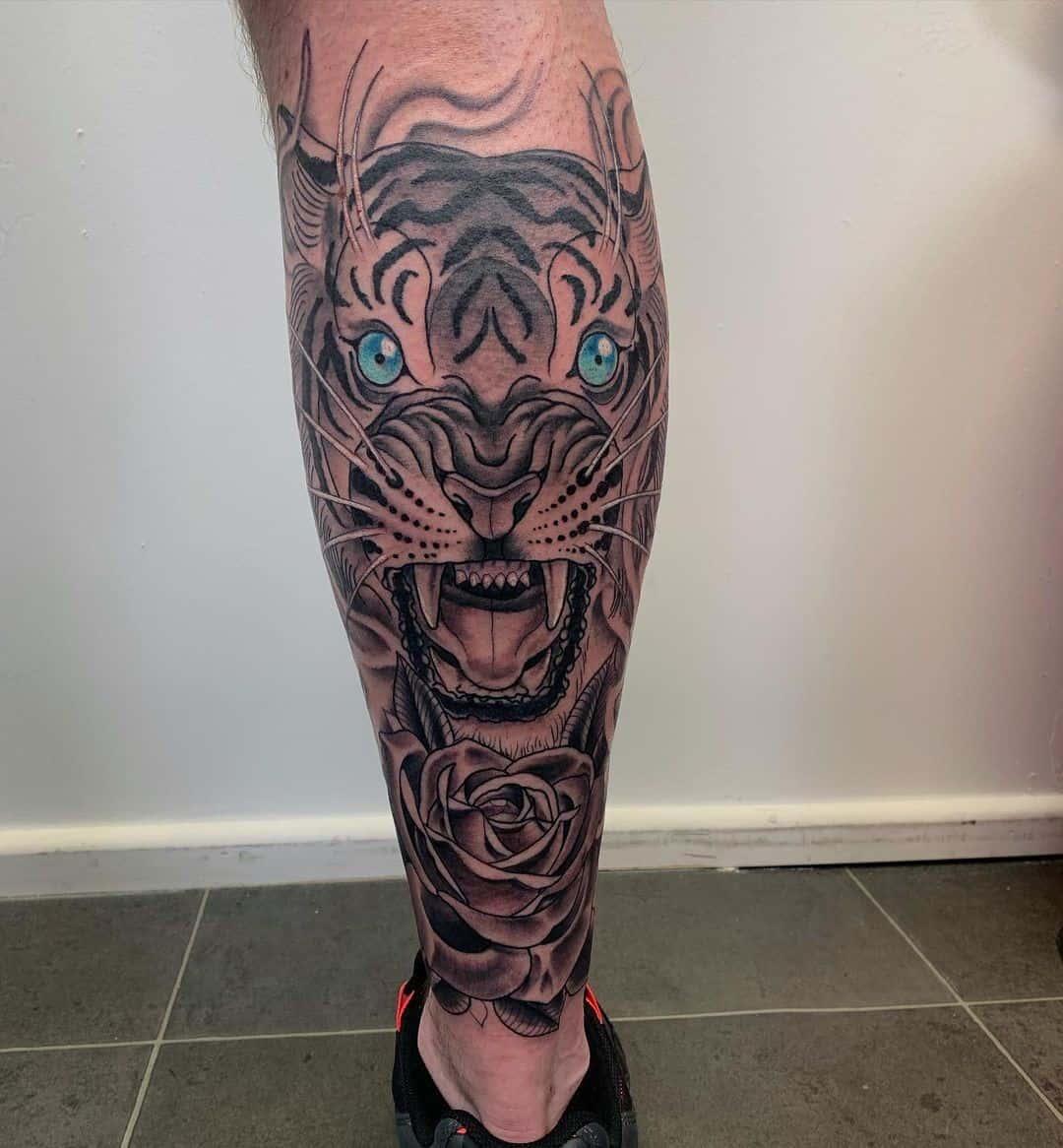 Tatuaje de tigre en la pantorrilla con ojos azules 
