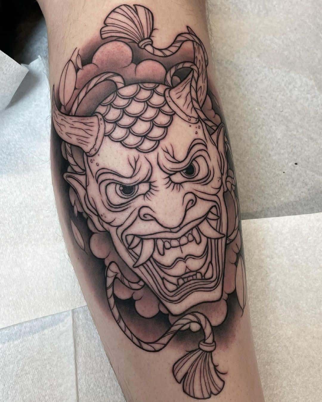 Tatuaje detallado de máscara oni en la pierna