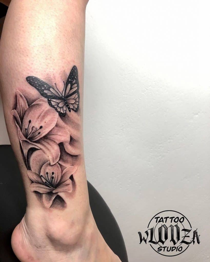 Tatuaje de lirio con una mariposa sobre la pierna