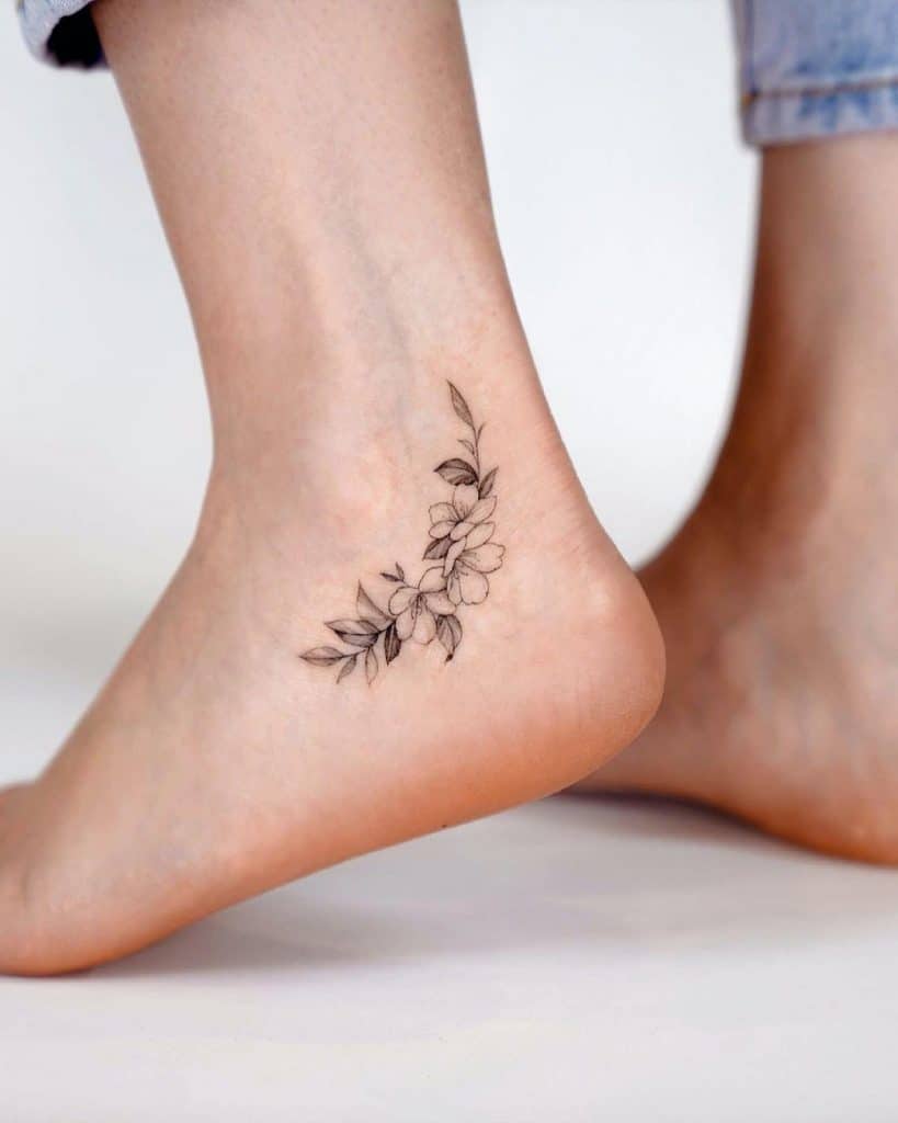Pequeño tatuaje de tobillo de flor en blanco y negro 