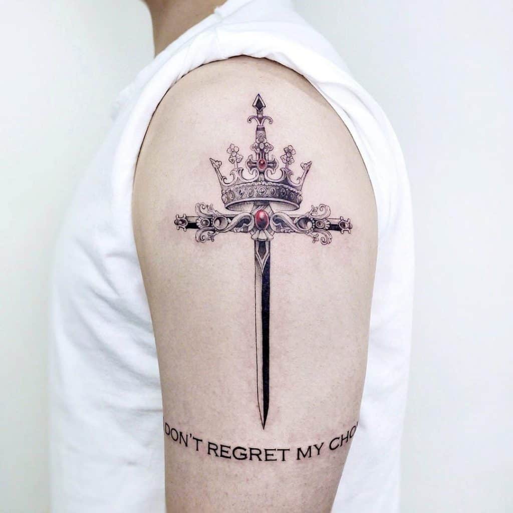 Tatuaje de corona y espada en el hombro.