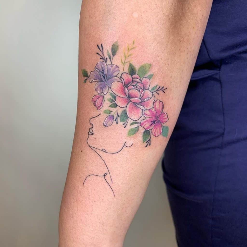 Tatuaje de corona y flores en el brazo.