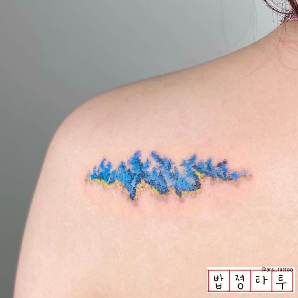 Pequeño y brillante tatuaje de hombro de onda azul 