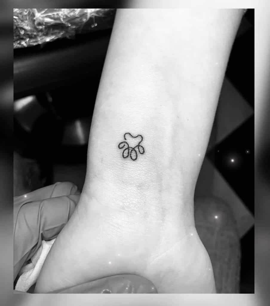 Pequeño tatuaje de pata de perro en el brazo