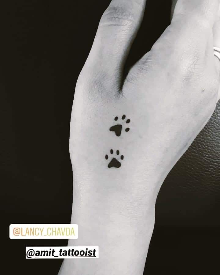 Tatuaje en la mano, dos patas de perro negro