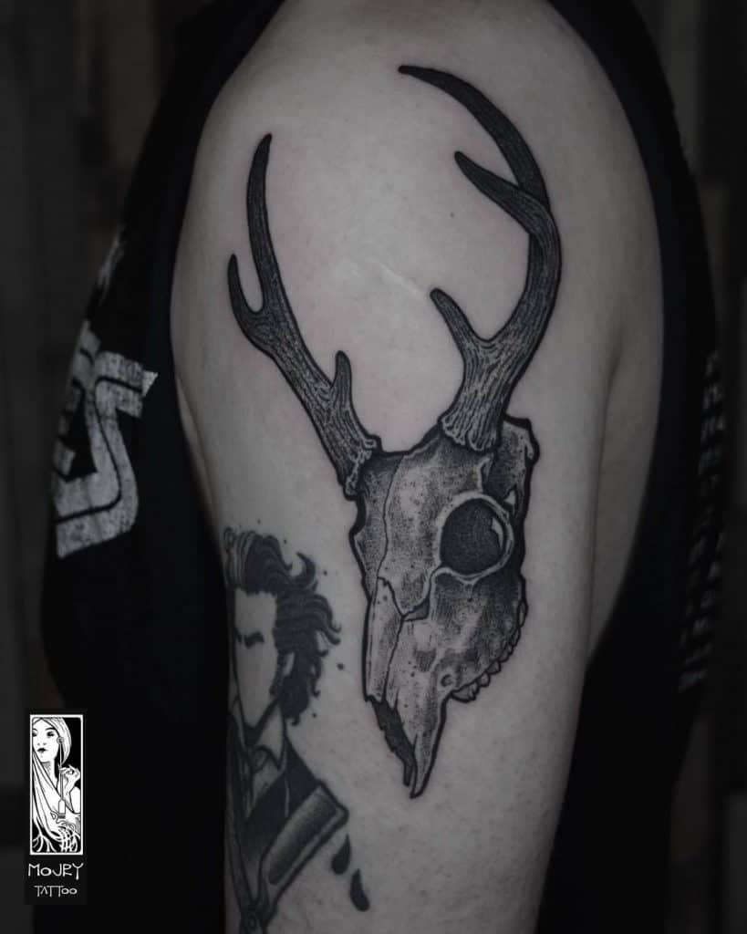 Tatuaje de cabeza de ciervo en la parte superior del brazo.
