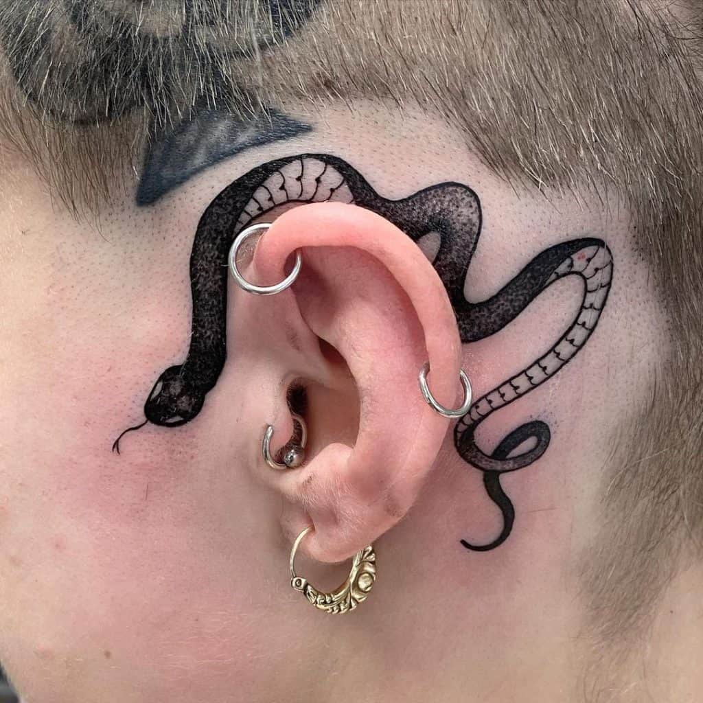 Tatuaje en el brazo, serpiente pequeña detrás de la oreja, tinta negra 